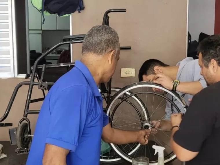 Homem consertando a roda de uma cadeira de rodas